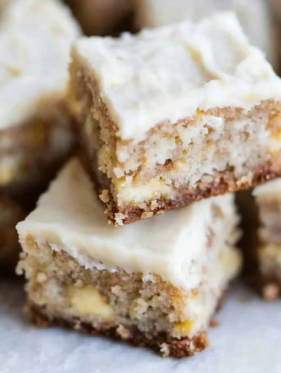A stack of cake squares with white frosting.