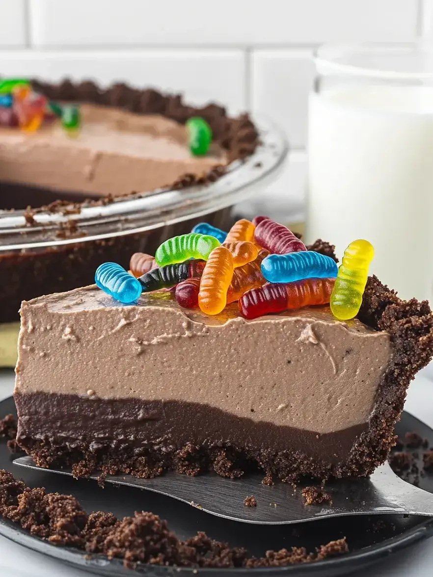 A slice of chocolate cake with gummy worms on top.