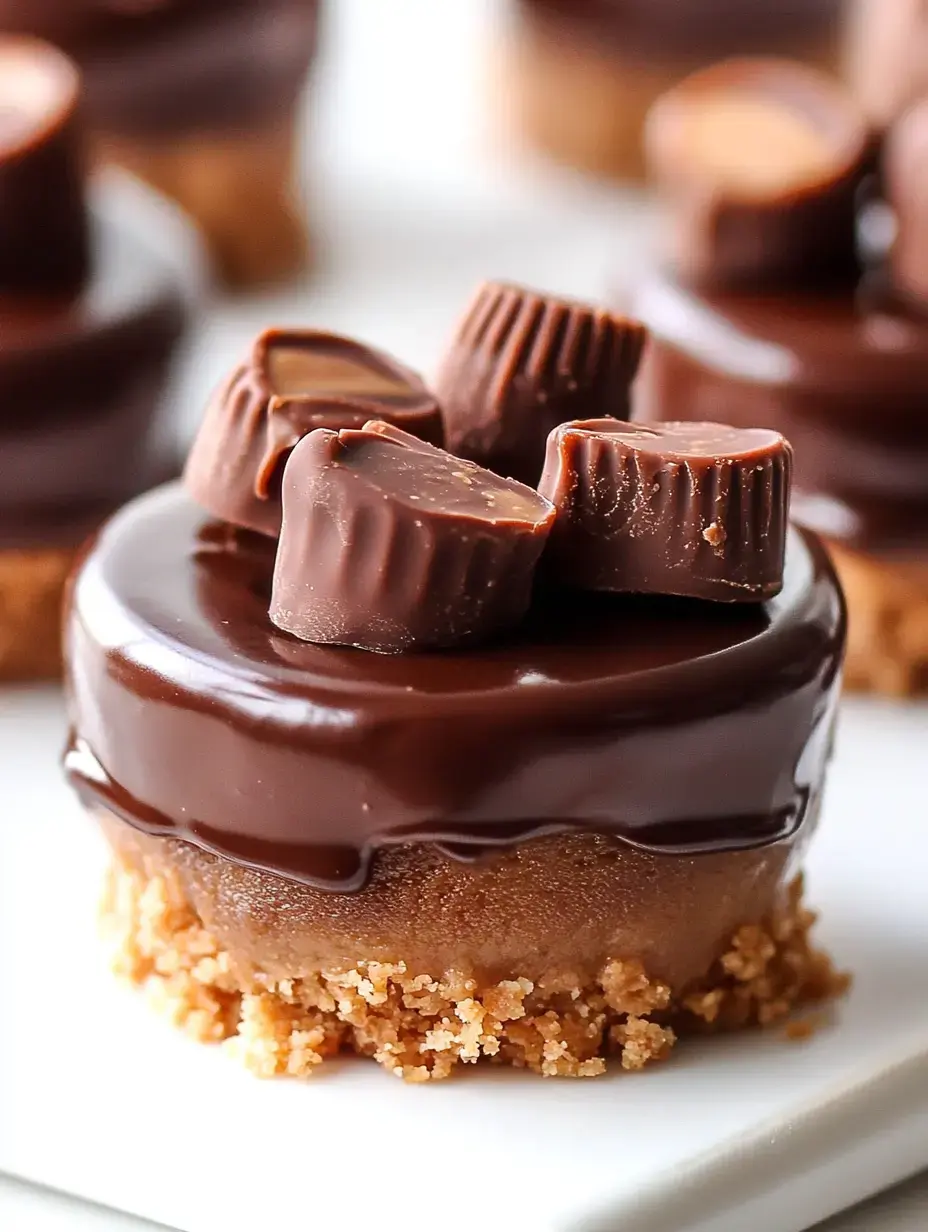 A close-up of a chocolate dessert topped with mini peanut butter cups on a crumbly base.