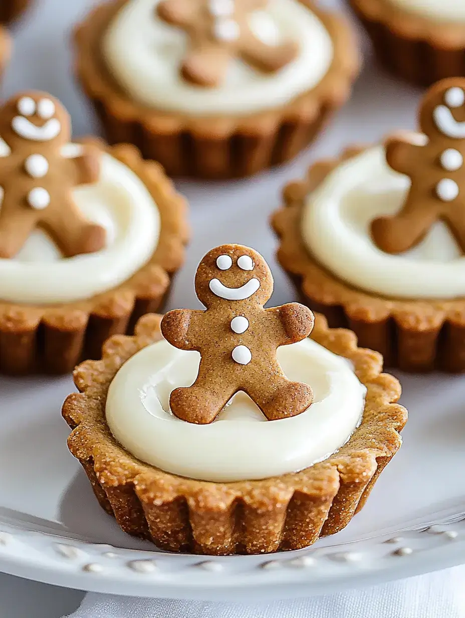 A close-up of mini tart desserts topped with cream cheese frosting and decorated with small gingerbread men.