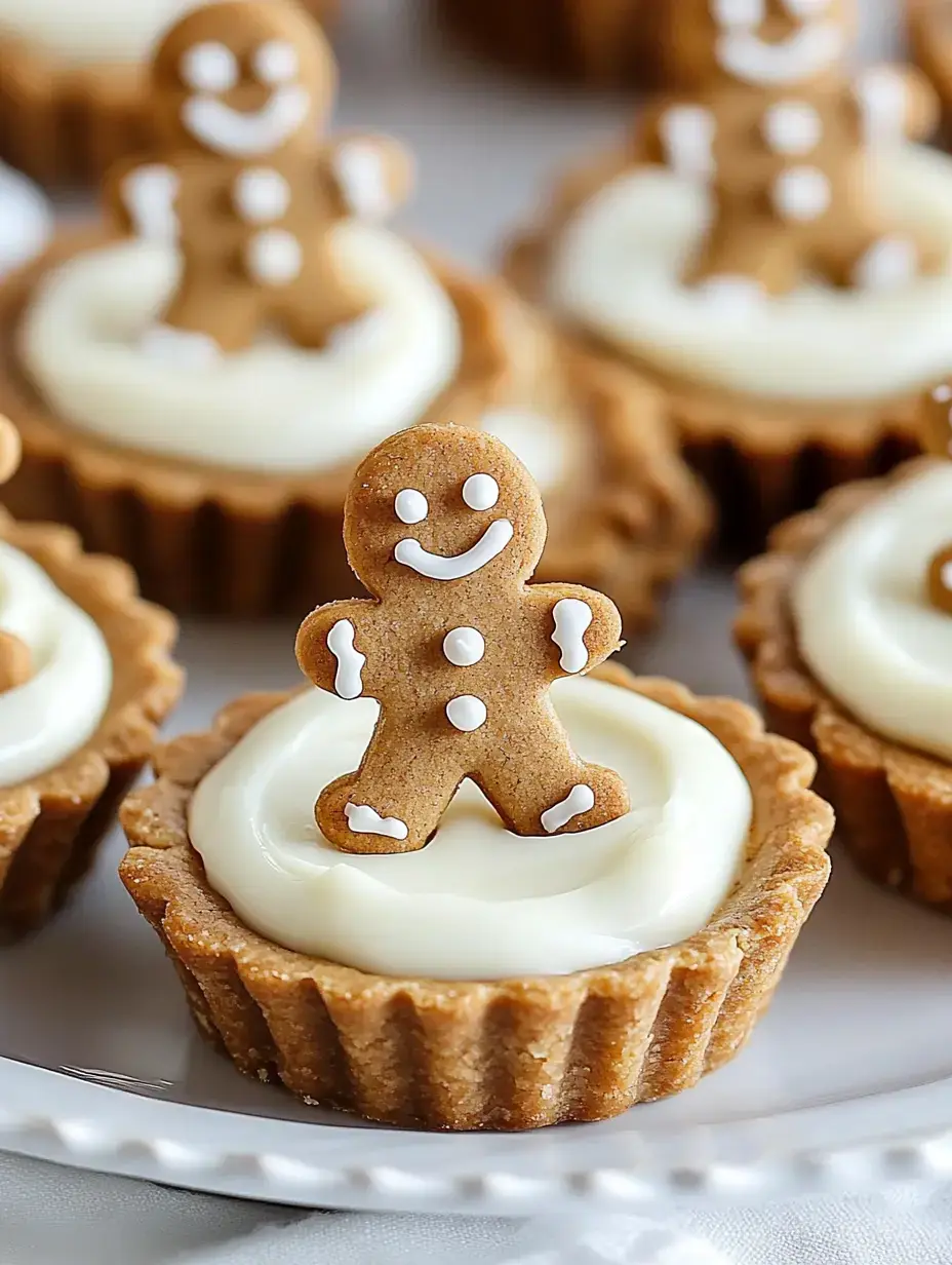 A close-up of small tart desserts topped with cream cheese frosting and decorated with gingerbread cookie figurines.