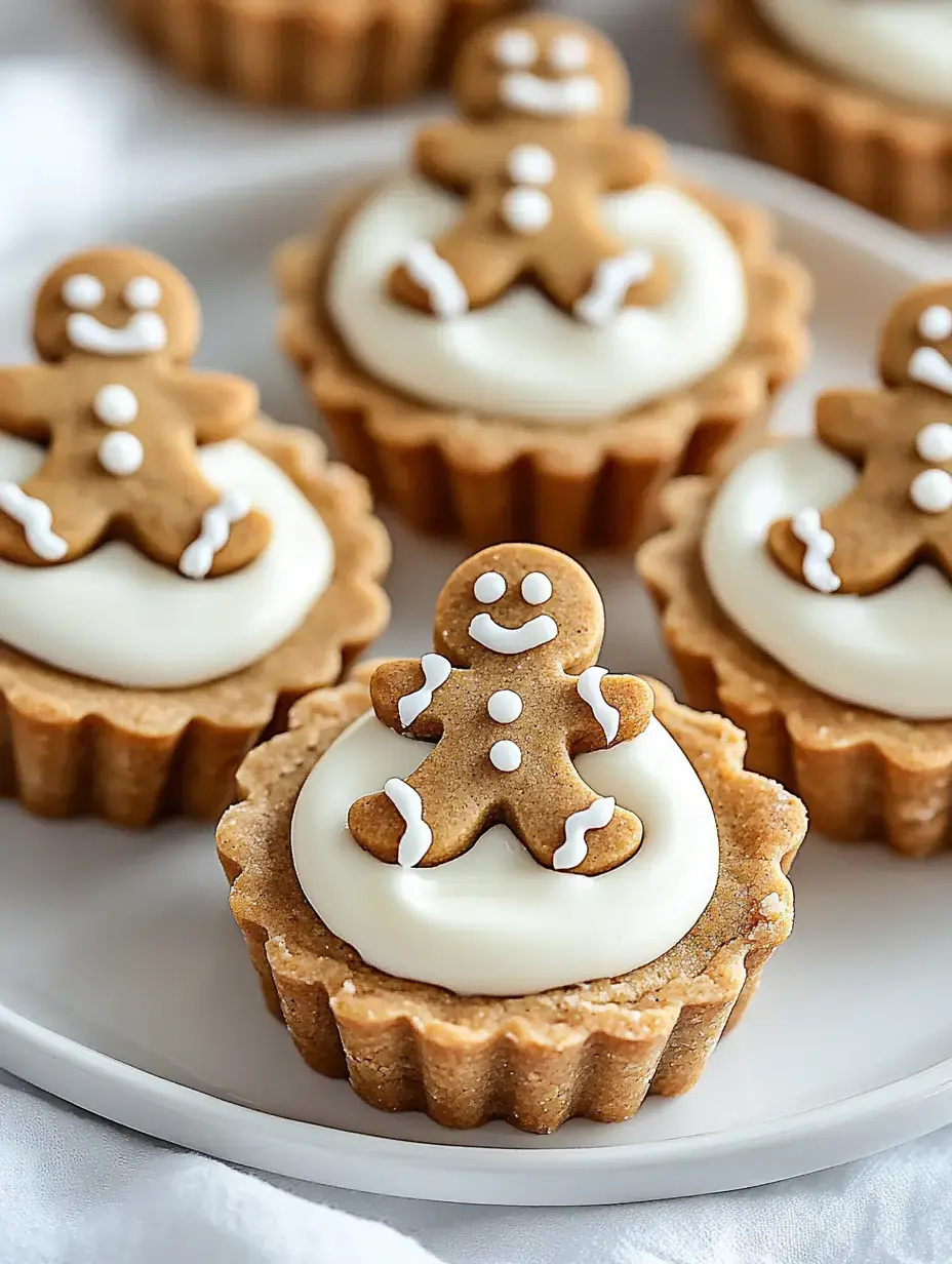 A plate of mini gingerbread cookie cups topped with white icing and decorated with small gingerbread men.