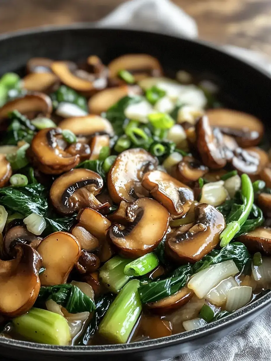 A close-up of sautéed mushrooms and green onions mixed with leafy greens in a skillet.