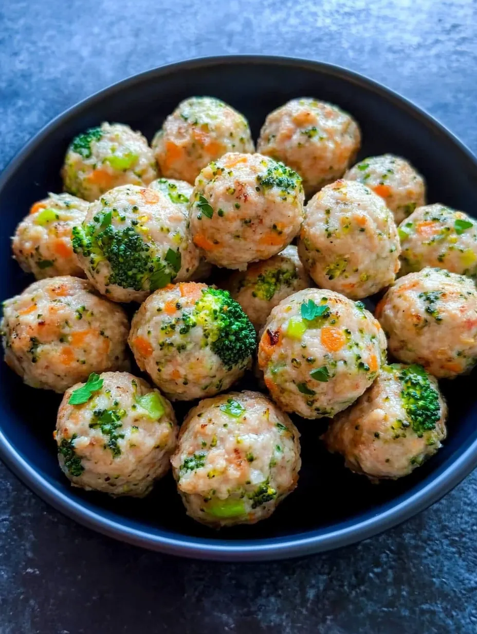 A bowl of meatballs with vegetables on top.