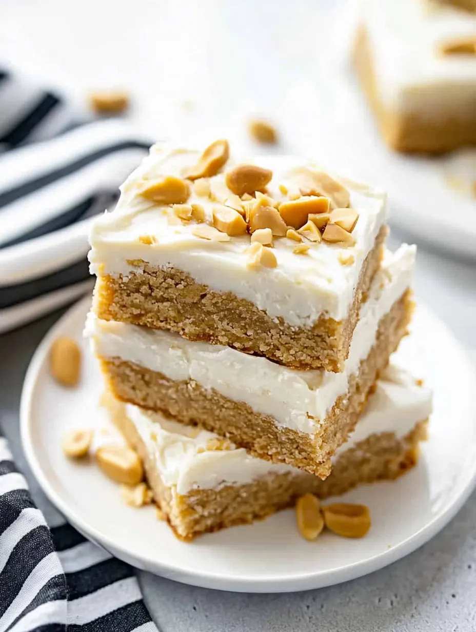 A stack of cake with white frosting and almonds on top.