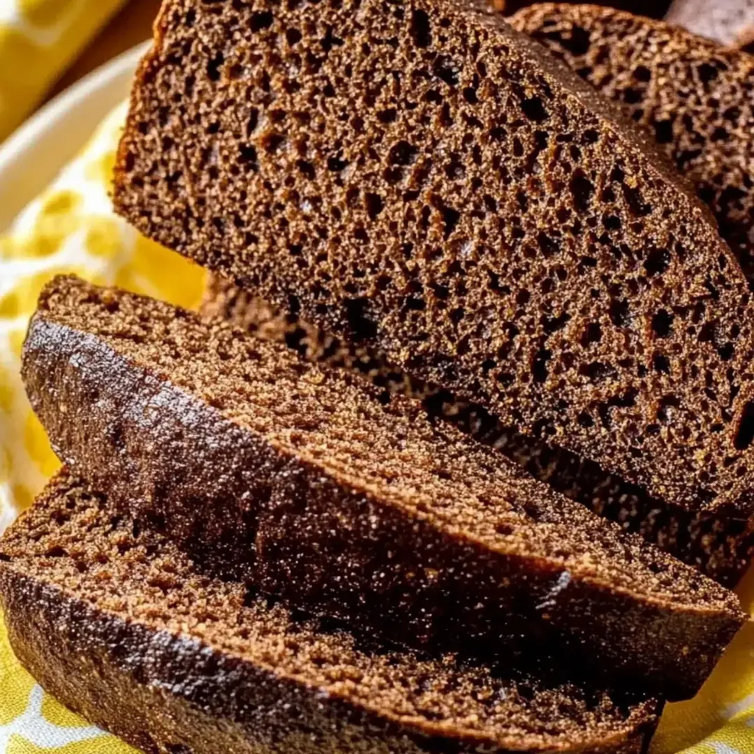 A brown loaf of bread is cut into slices and placed on a plate.