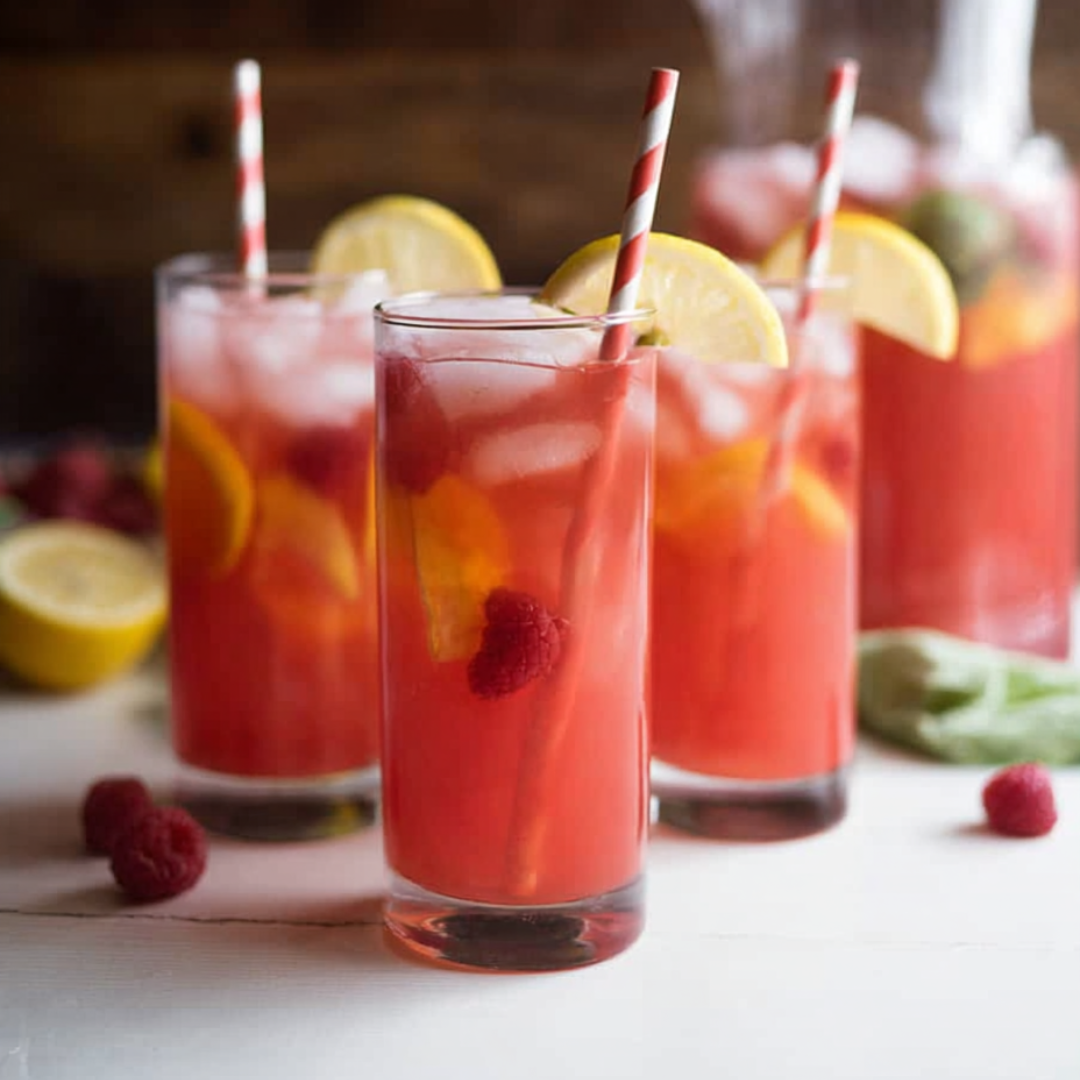 Three glasses of pink lemonade with straws in them.