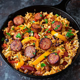 A delicious meal of sausage and rice in a black pan.