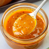 Orange mustard sauce in a jar with a spoon.