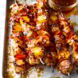 A tray of meat skewers with peppers and sauce.