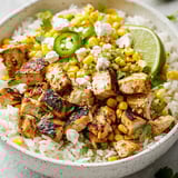 A bowl of rice with chicken and vegetables.