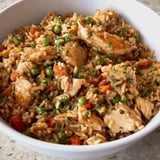 A bowl of rice with chicken and peas.