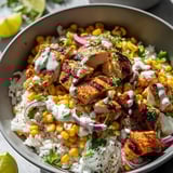 A bowl of food with rice, corn, chicken, and onions.
