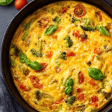 A close up of a vegetable omelet with broccoli and tomatoes.