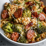 A bowl of pasta with sausage and broccoli.