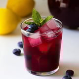 A glass of blueberry juice with a lemon wedge on top.