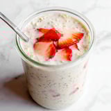 A glass of yogurt with strawberries.